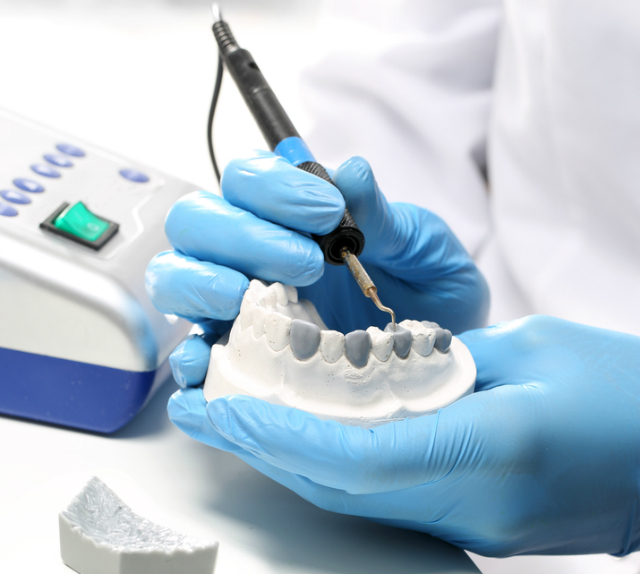 fotografia-das-mãos-de-protético-enquanto-realiza-processo-de-enceramento-e-escultura-dental